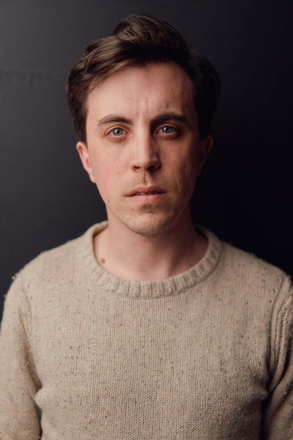 Felix Trench wearing a rough wool jumper against a black background